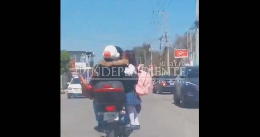 Padre transporta a su hija parada en el escape de una motocicleta