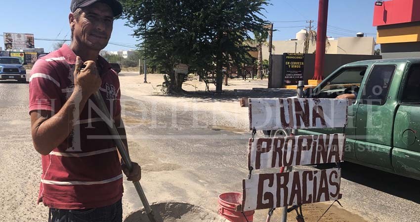 A cambio de una propina, este ciudadano tapa baches en calles de La Paz